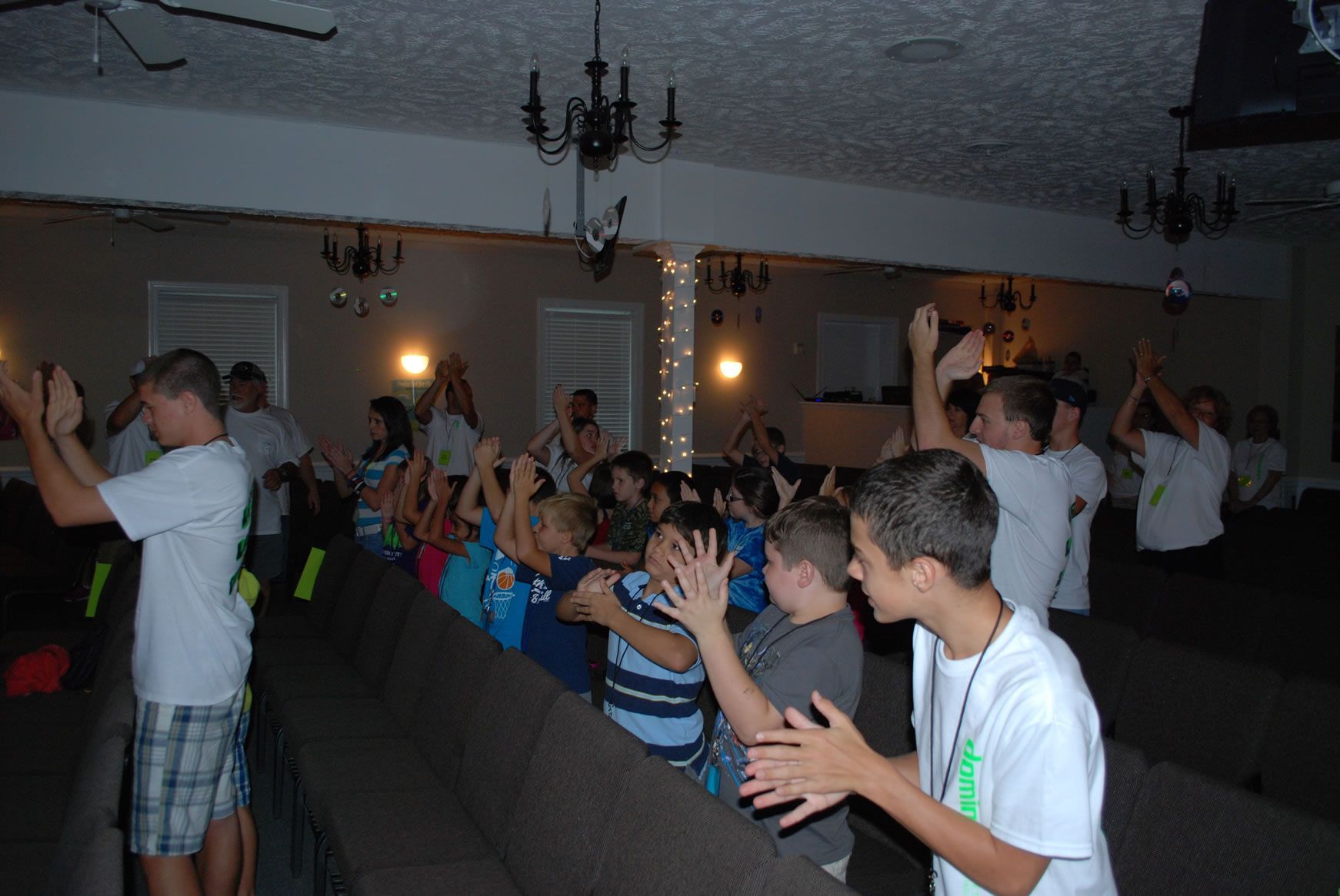 A group of children are clapping their hands in a dark room