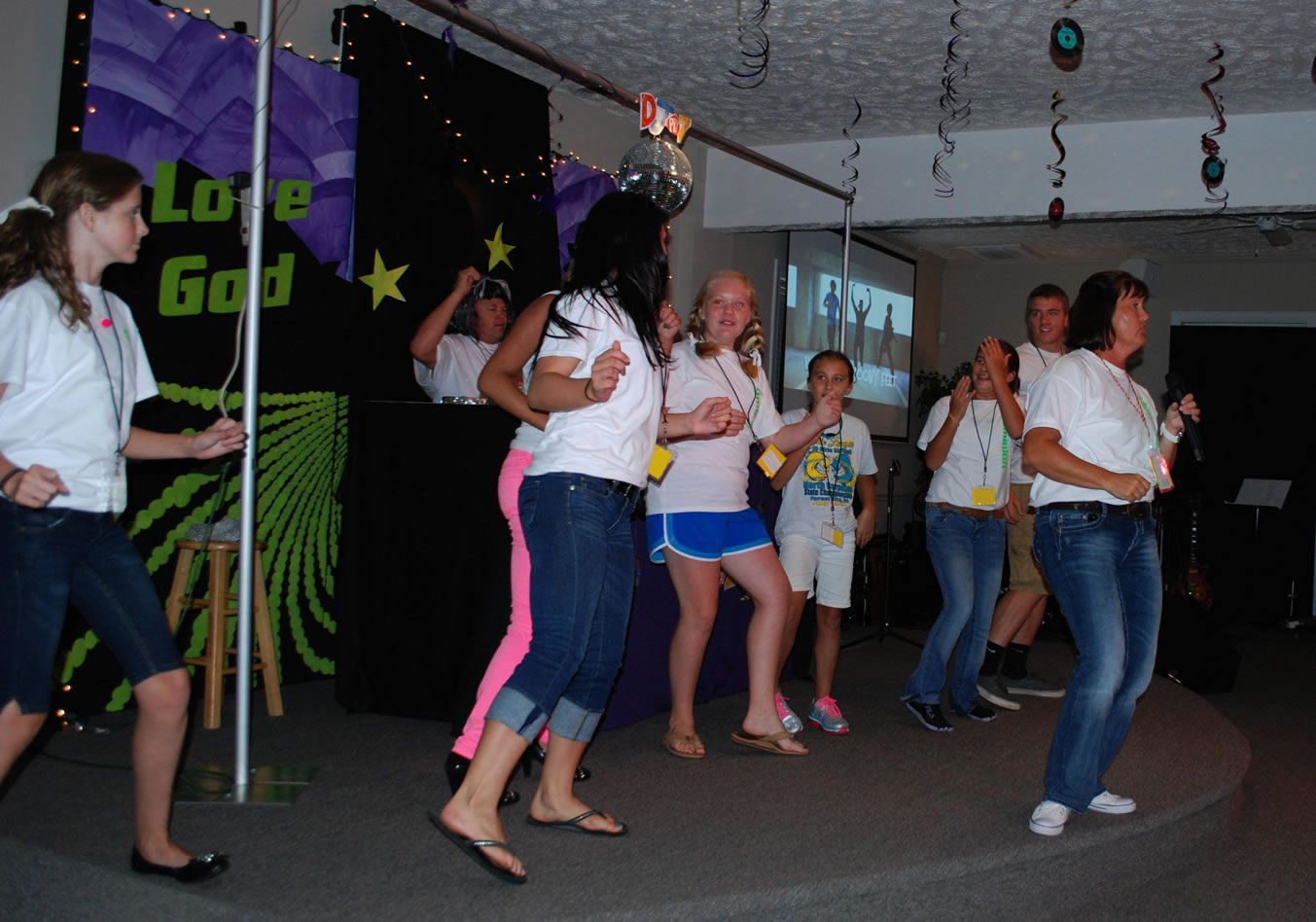 A group of people are dancing in front of a sign that says love god