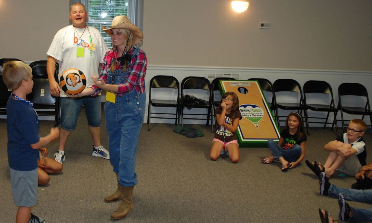 A group of children are playing a game of cornhole in a room.