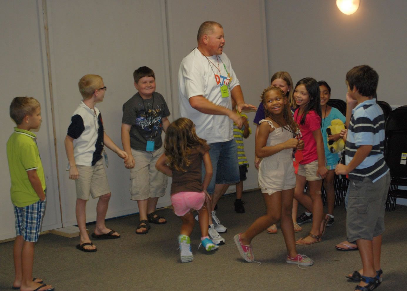 A group of children are standing around a man in a white shirt