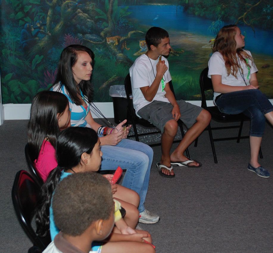 A group of people are sitting in chairs in front of a painting