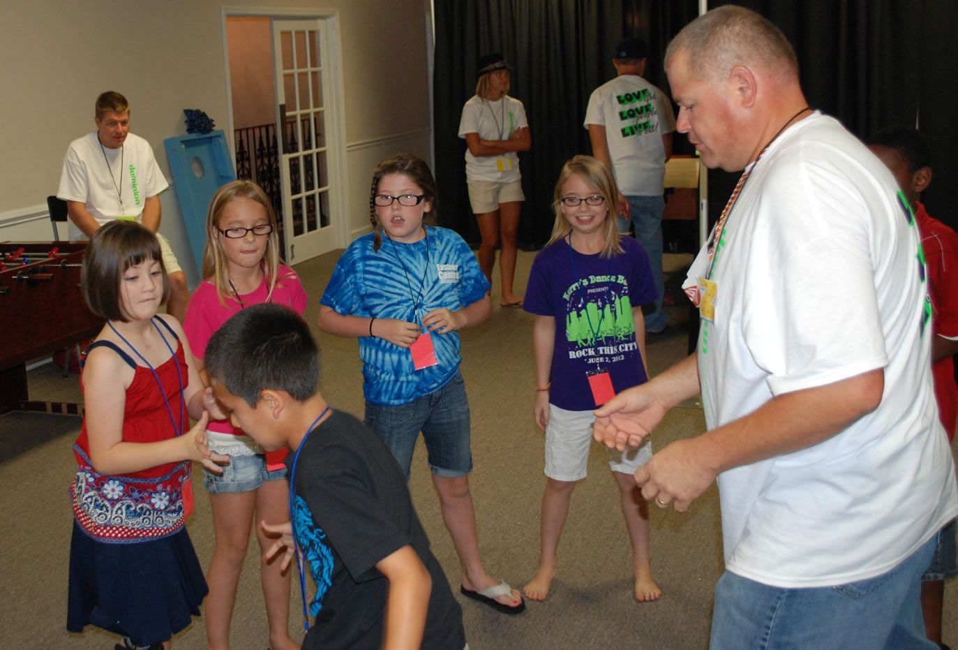 A group of children are standing around a man in a white shirt