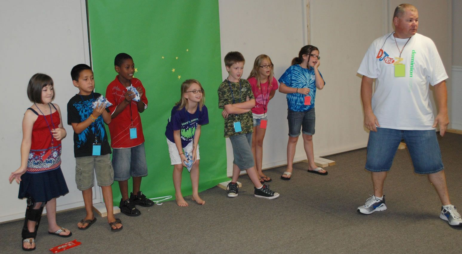 A group of children are standing in front of a green screen