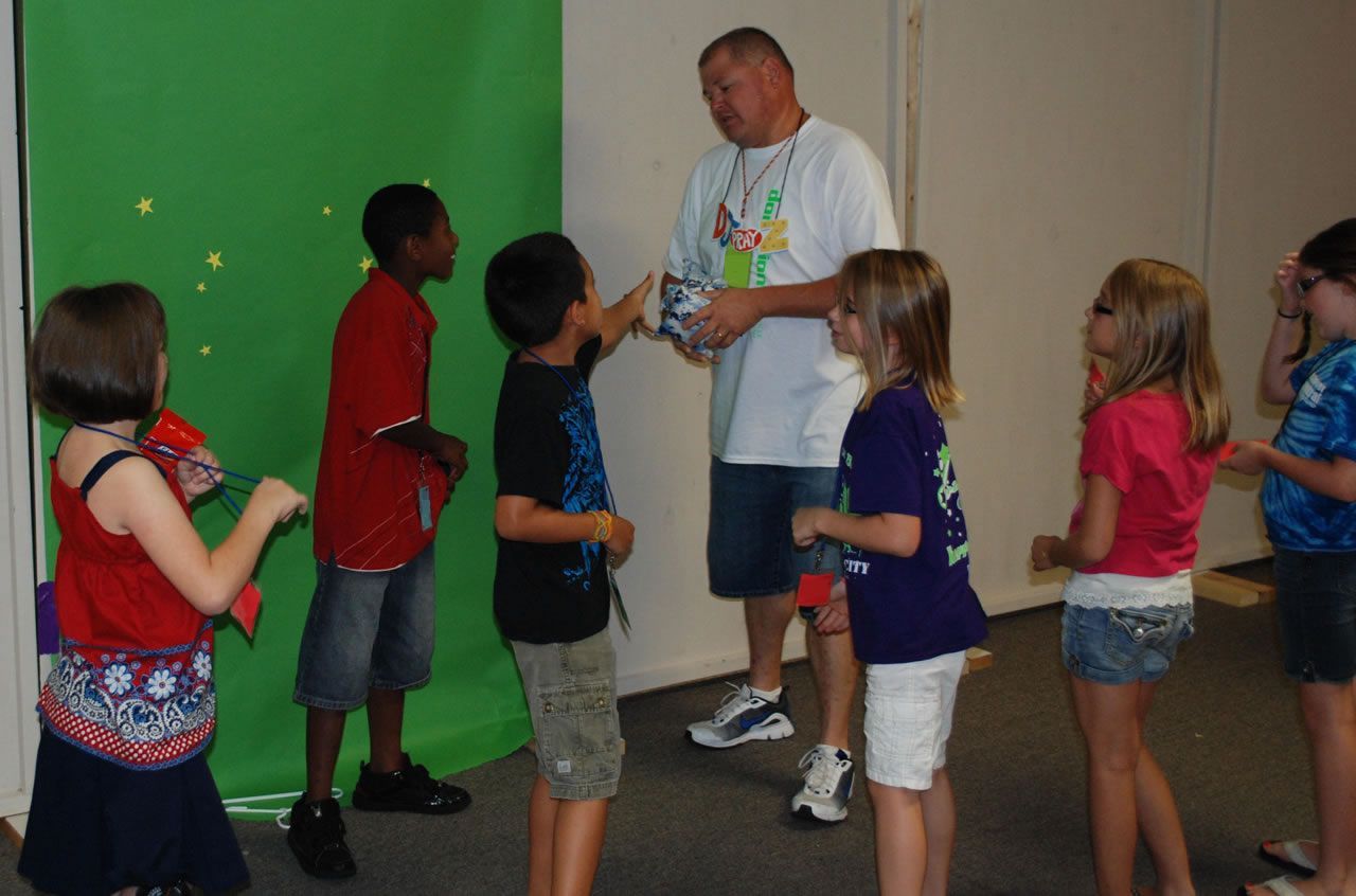 A group of children standing in front of a green screen