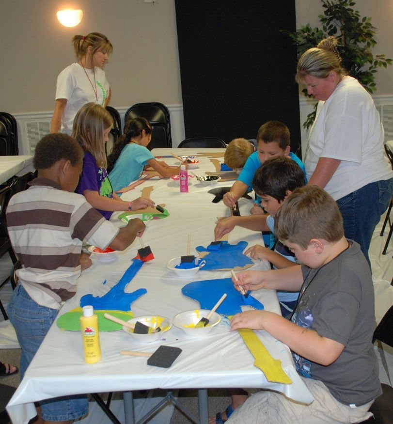 A group of children are sitting around a table painting