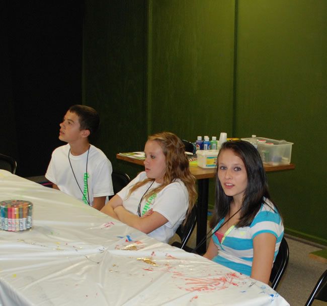 Three people sit at a table with a white table cloth