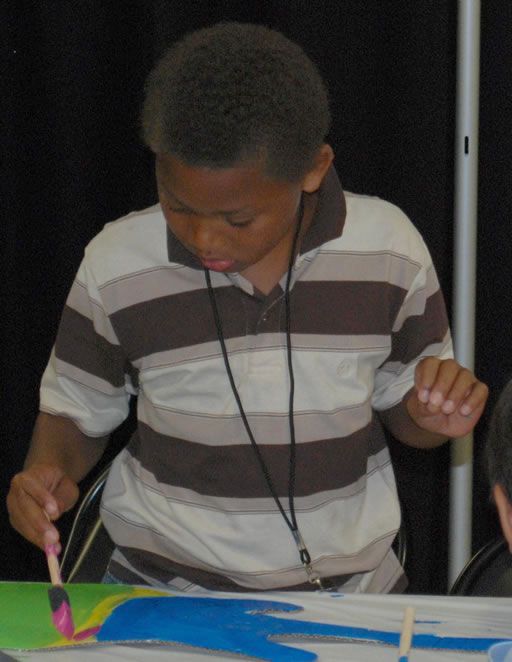 A young boy in a striped shirt is holding a brush
