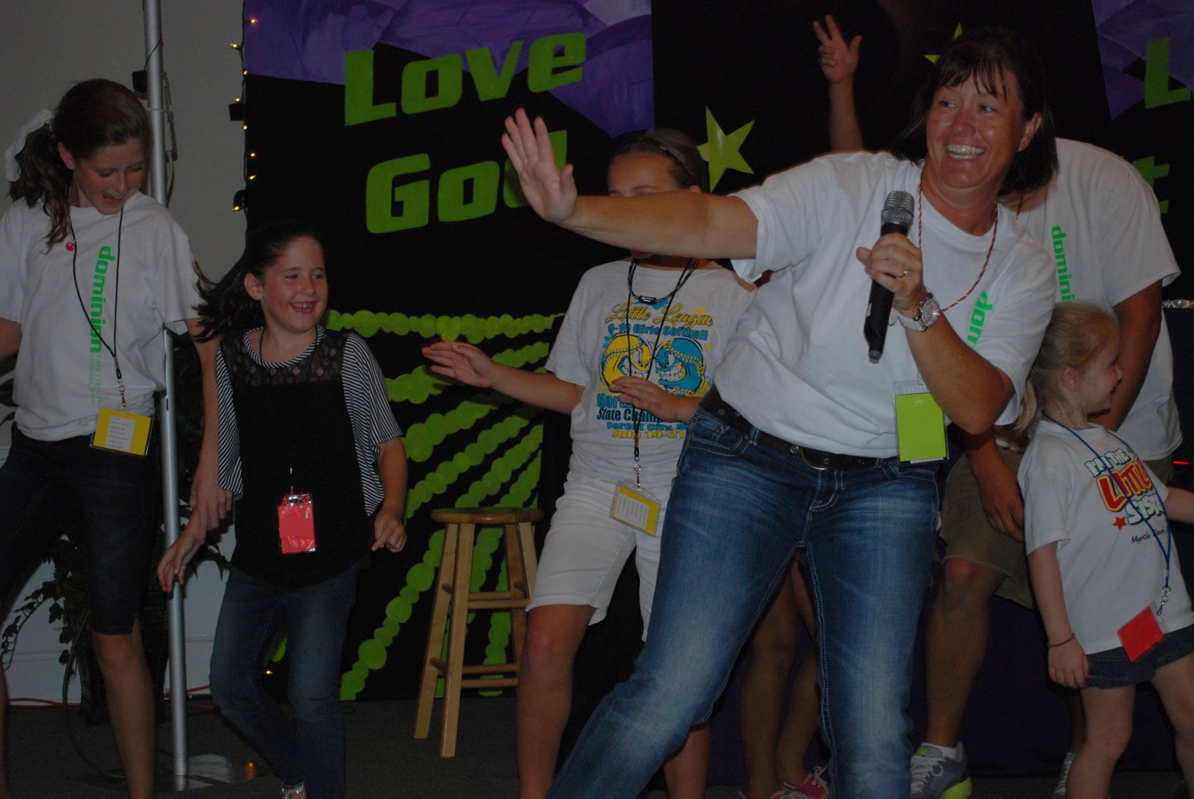 A woman is singing into a microphone in front of a sign that says love