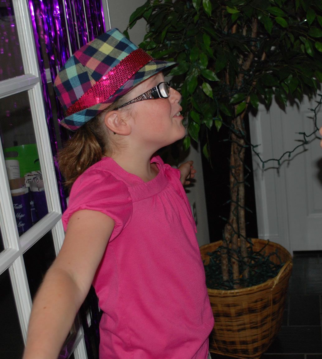 A little girl wearing a pink shirt and a hat