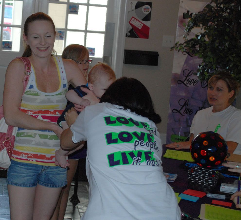 A woman holding a baby wearing a shirt that says love people live