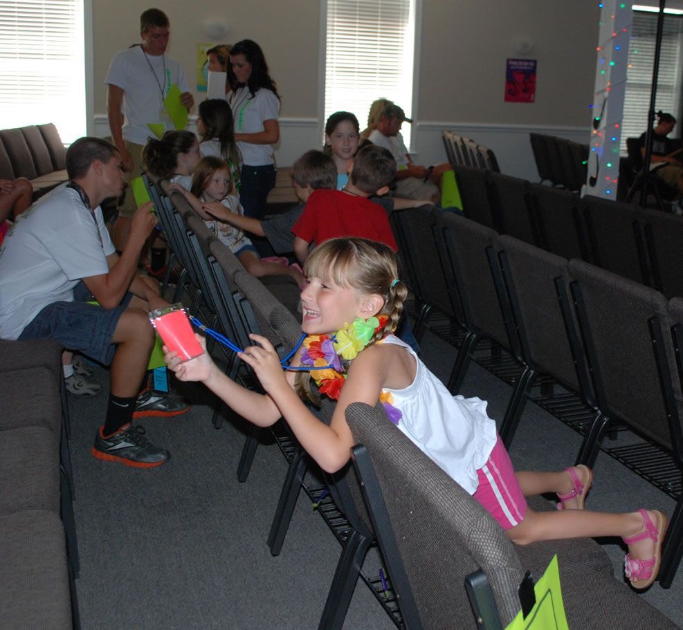 A girl is sitting in a row of chairs with a yellow tag that says ' l ' on it