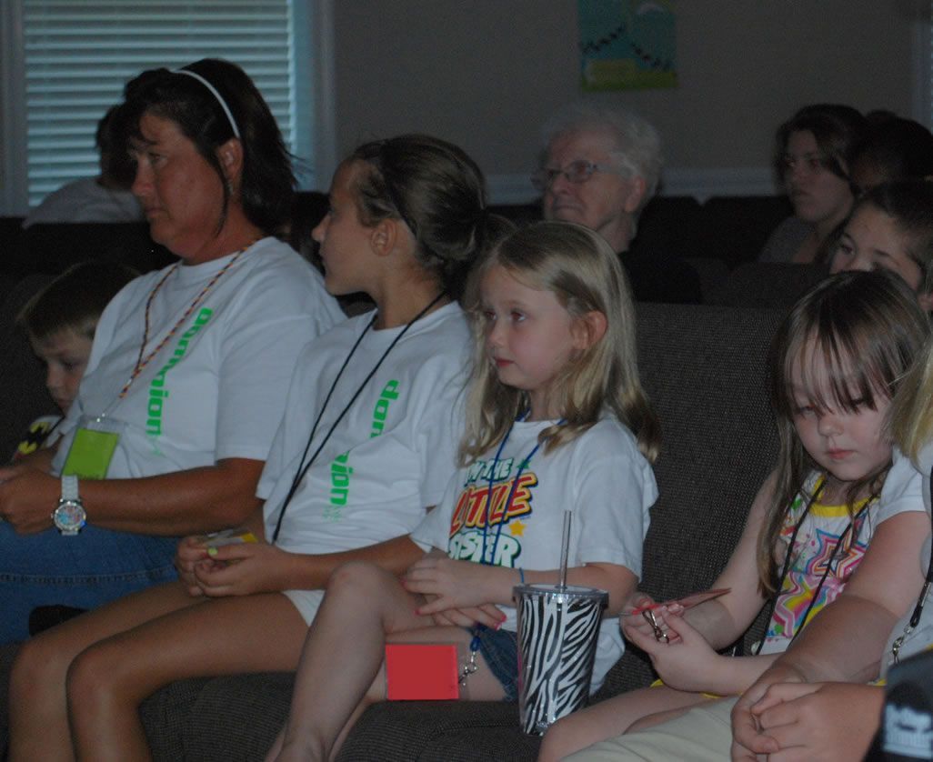 A group of people sitting on a couch with one girl wearing a t-shirt that says 