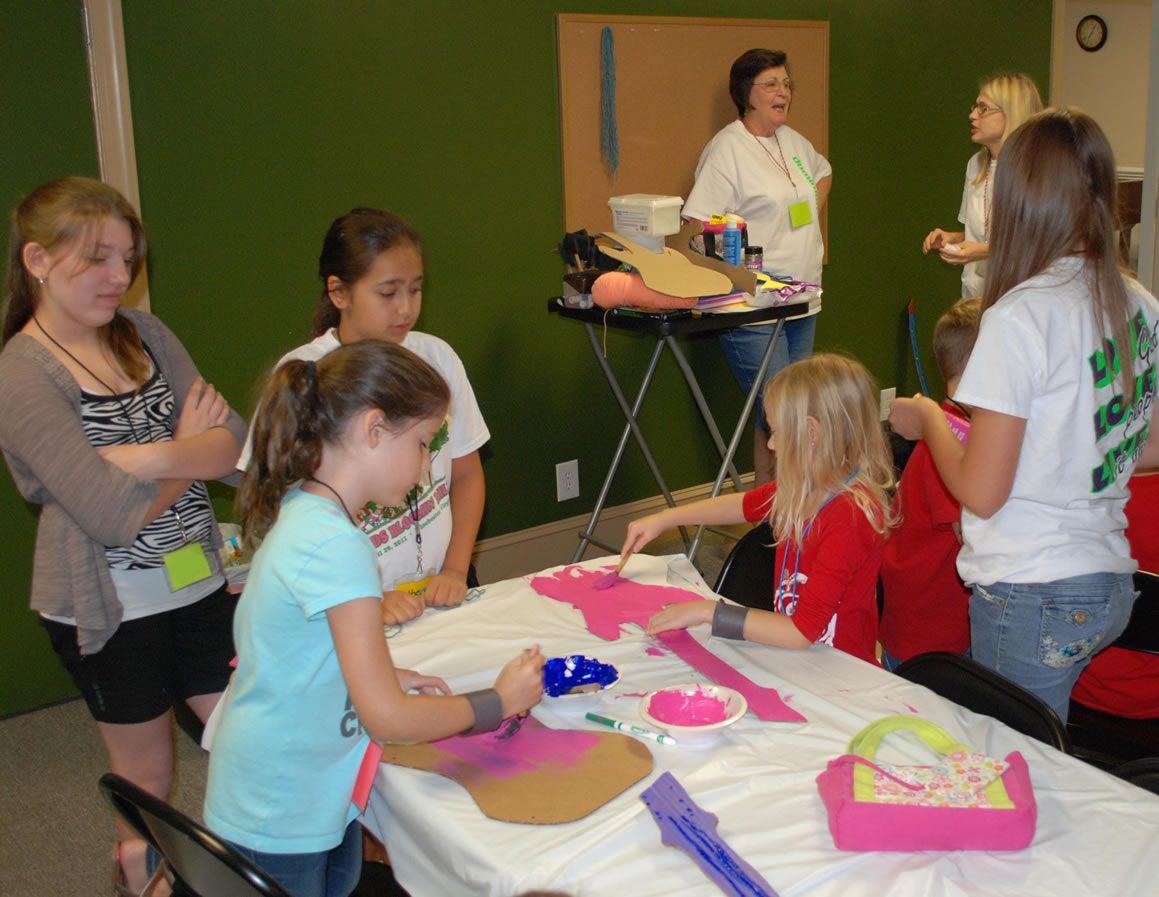 A group of young girls are sitting around a table making crafts