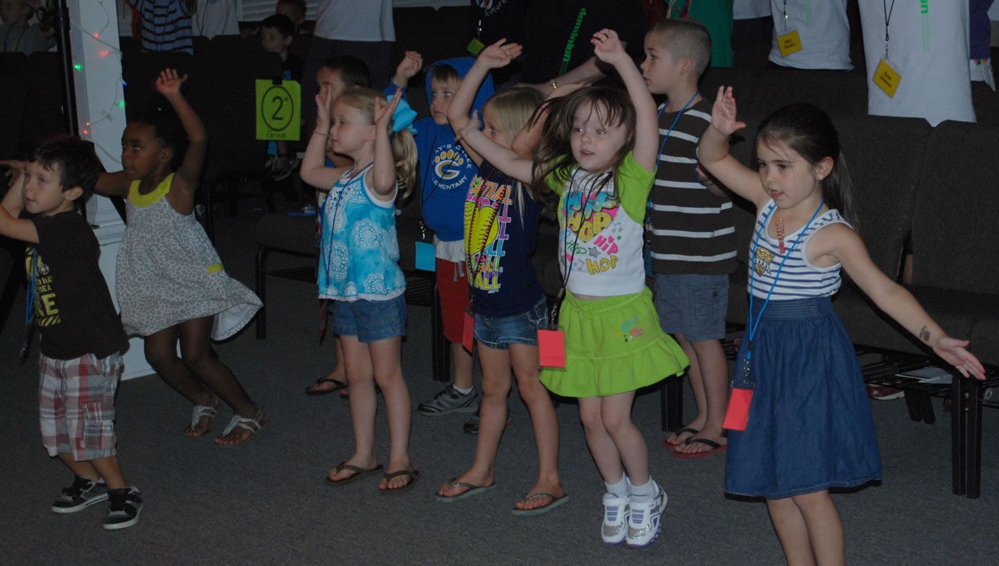 A group of children are dancing together in a dark room.