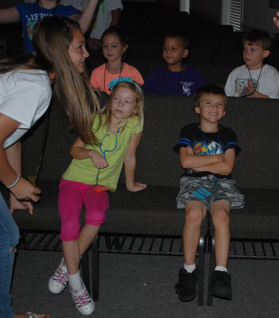 A girl in a yellow shirt is talking to a boy in a black shirt