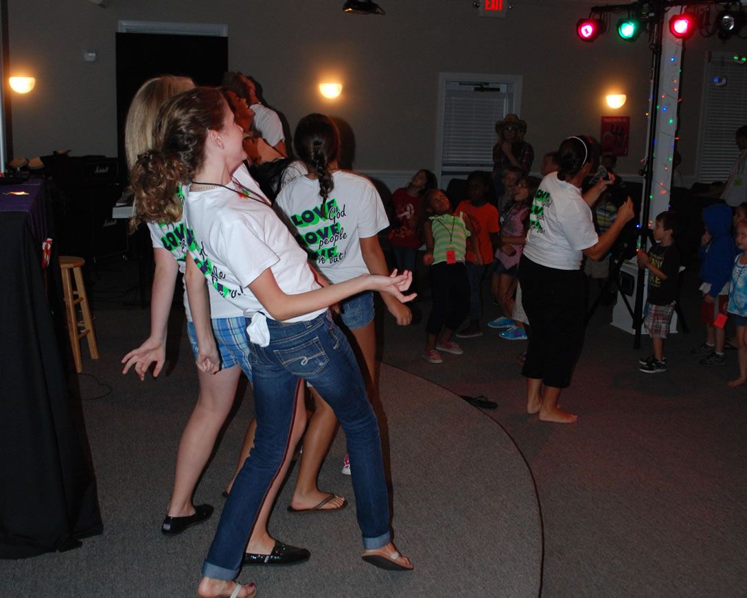 A group of people are dancing in a room and one girl is wearing a shirt that says science rock