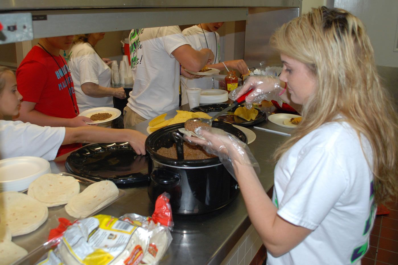 A woman in a white shirt is preparing food in a kitchen