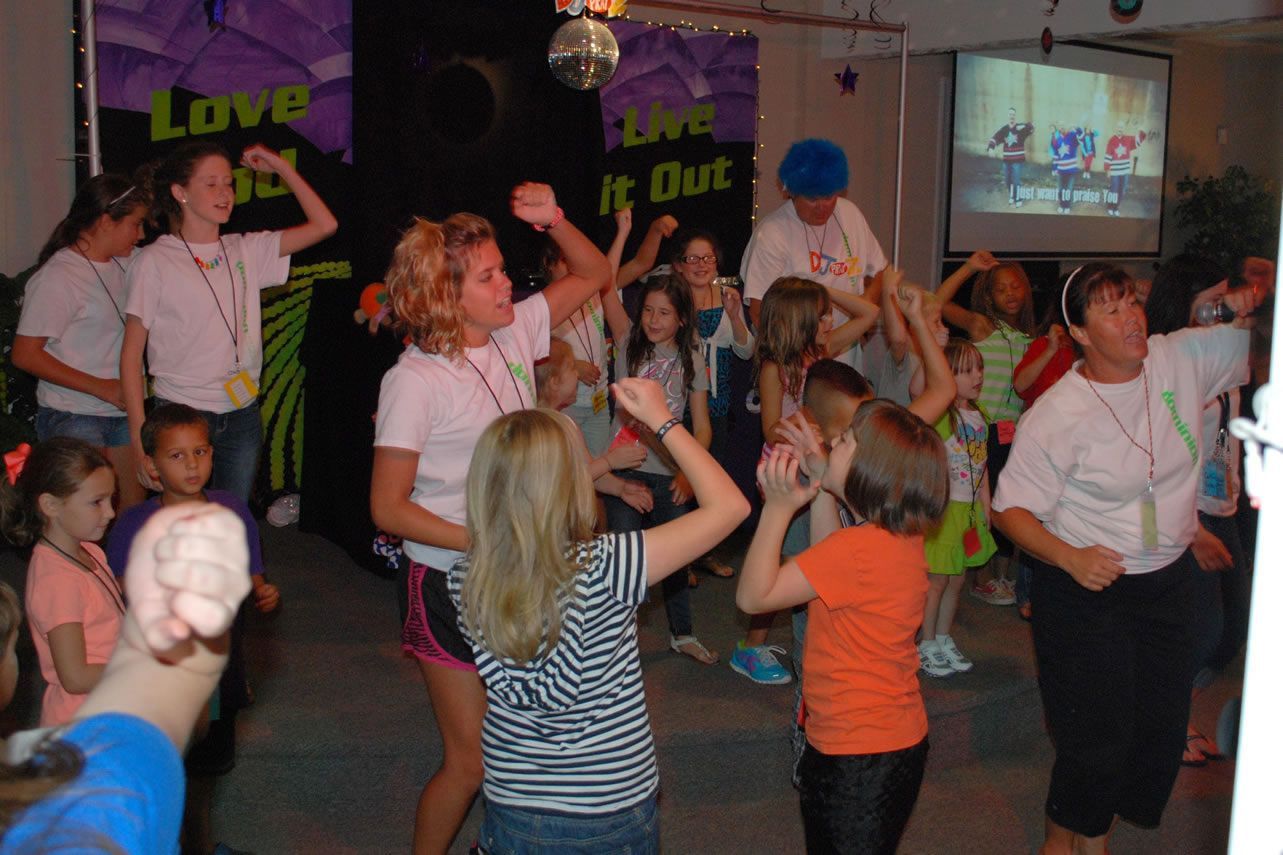A group of children are dancing in front of a sign that says love it out