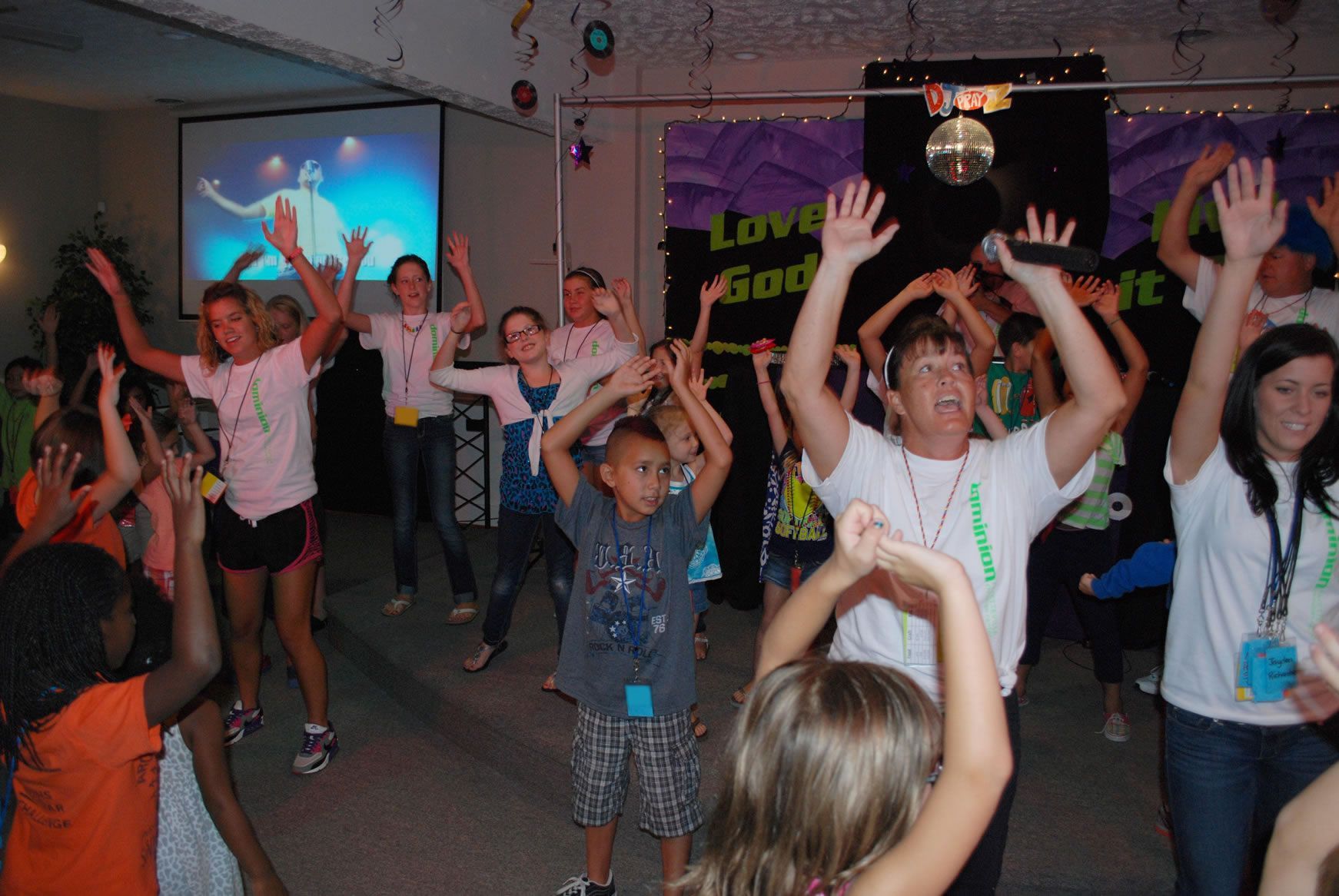 A group of children are dancing in front of a sign that says love