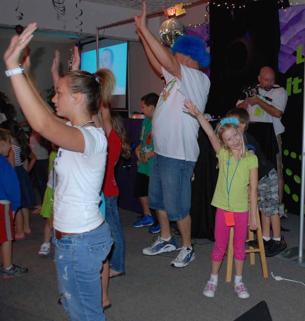 A group of people are dancing in front of a sign that says it