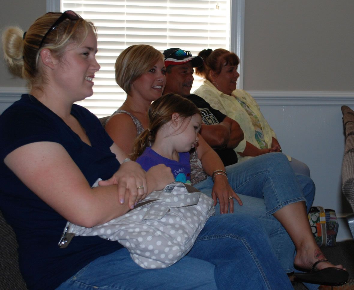 A group of people are sitting on a couch in front of a window