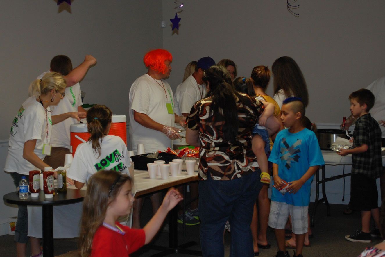 A group of people standing around a table with a girl wearing a red shirt that says love