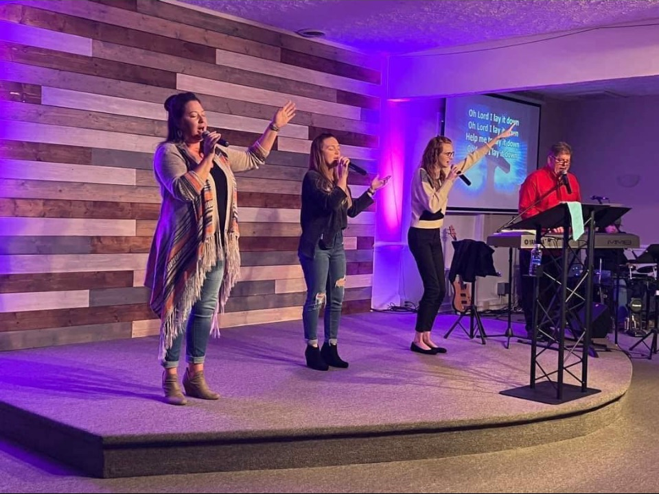 A group of women are standing on a stage singing into microphones.