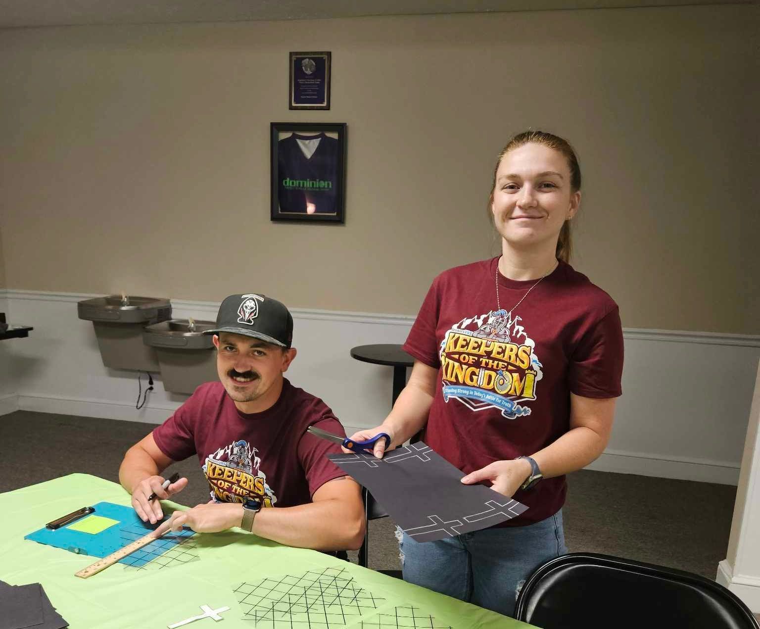 A man and a woman are sitting at a table wearing shirts that say lincoln