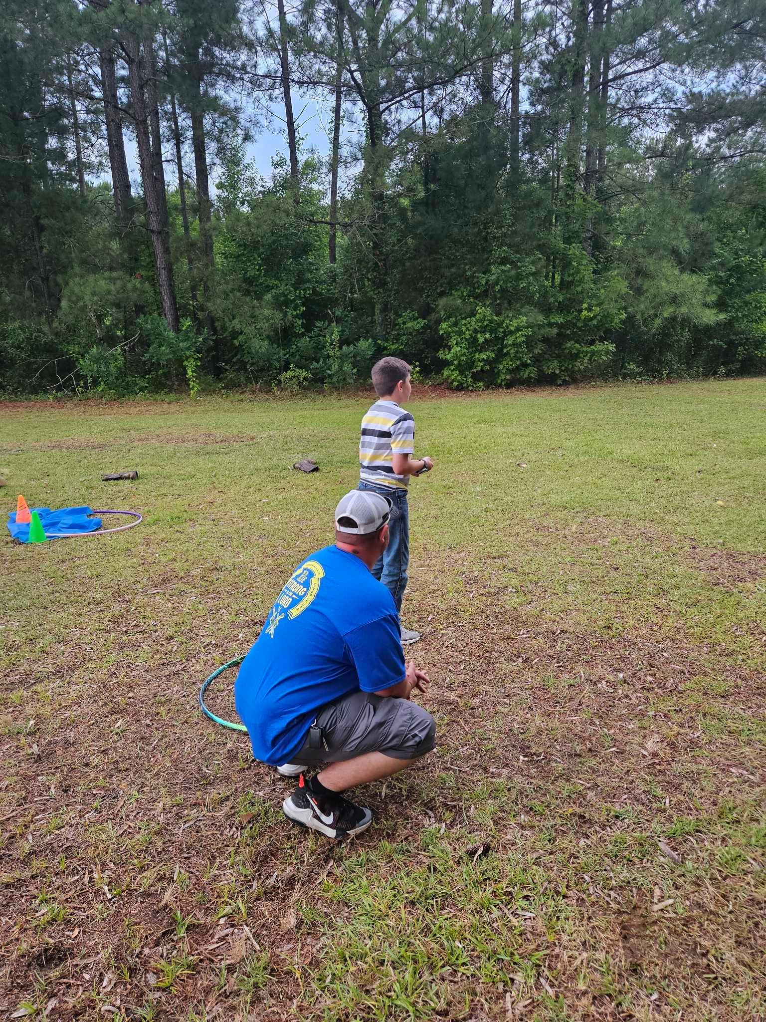 A man and a boy are playing with a remote control in a field.