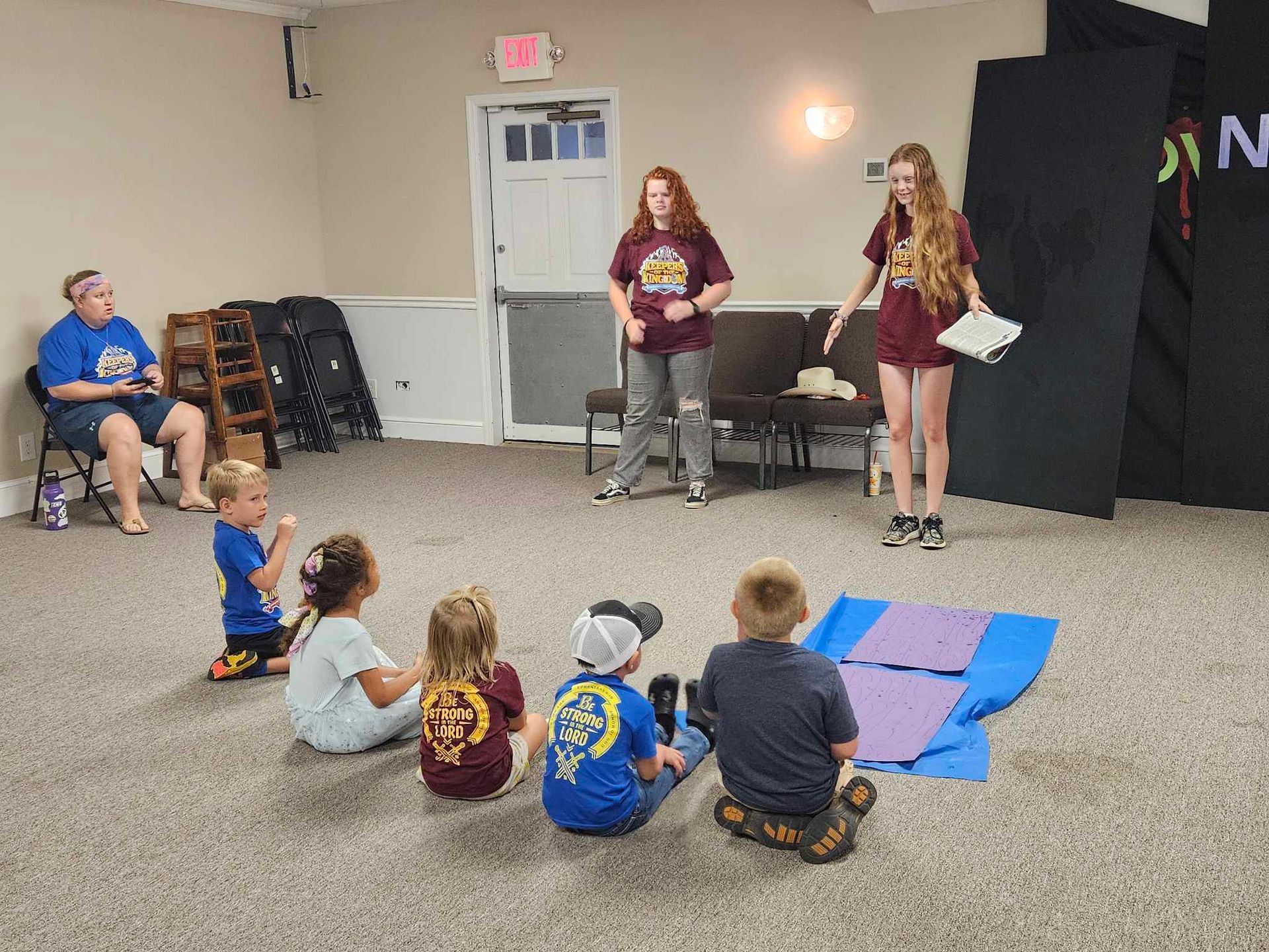 A group of children are sitting on the floor in a room.