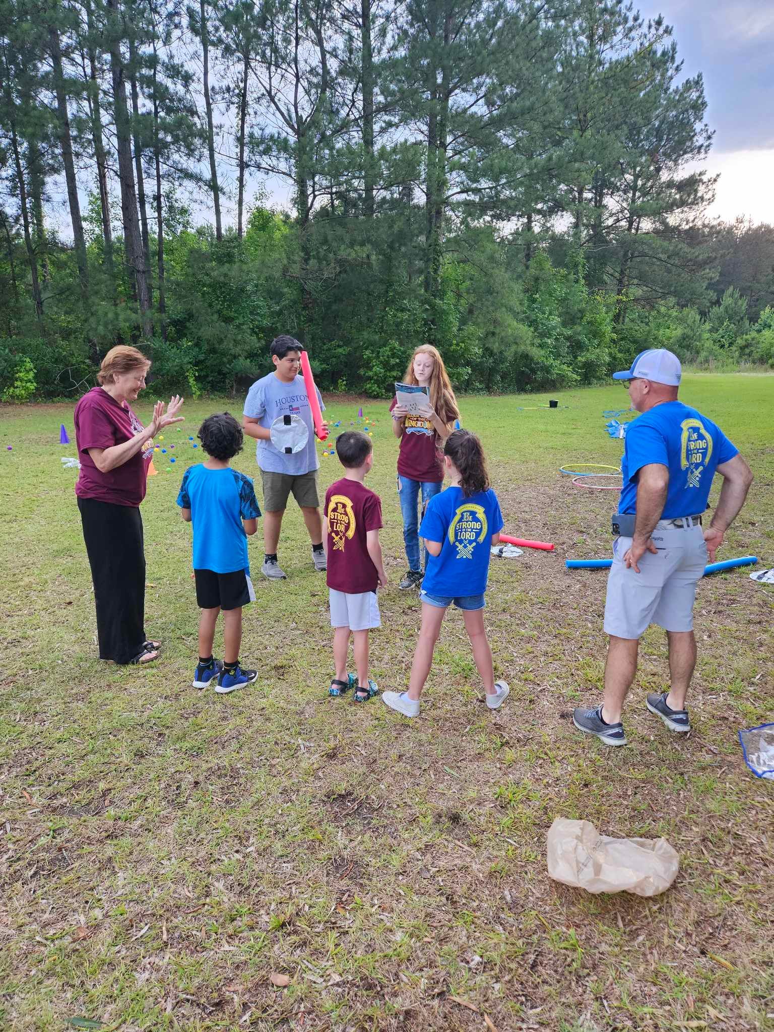A group of people are standing in a field talking to each other.