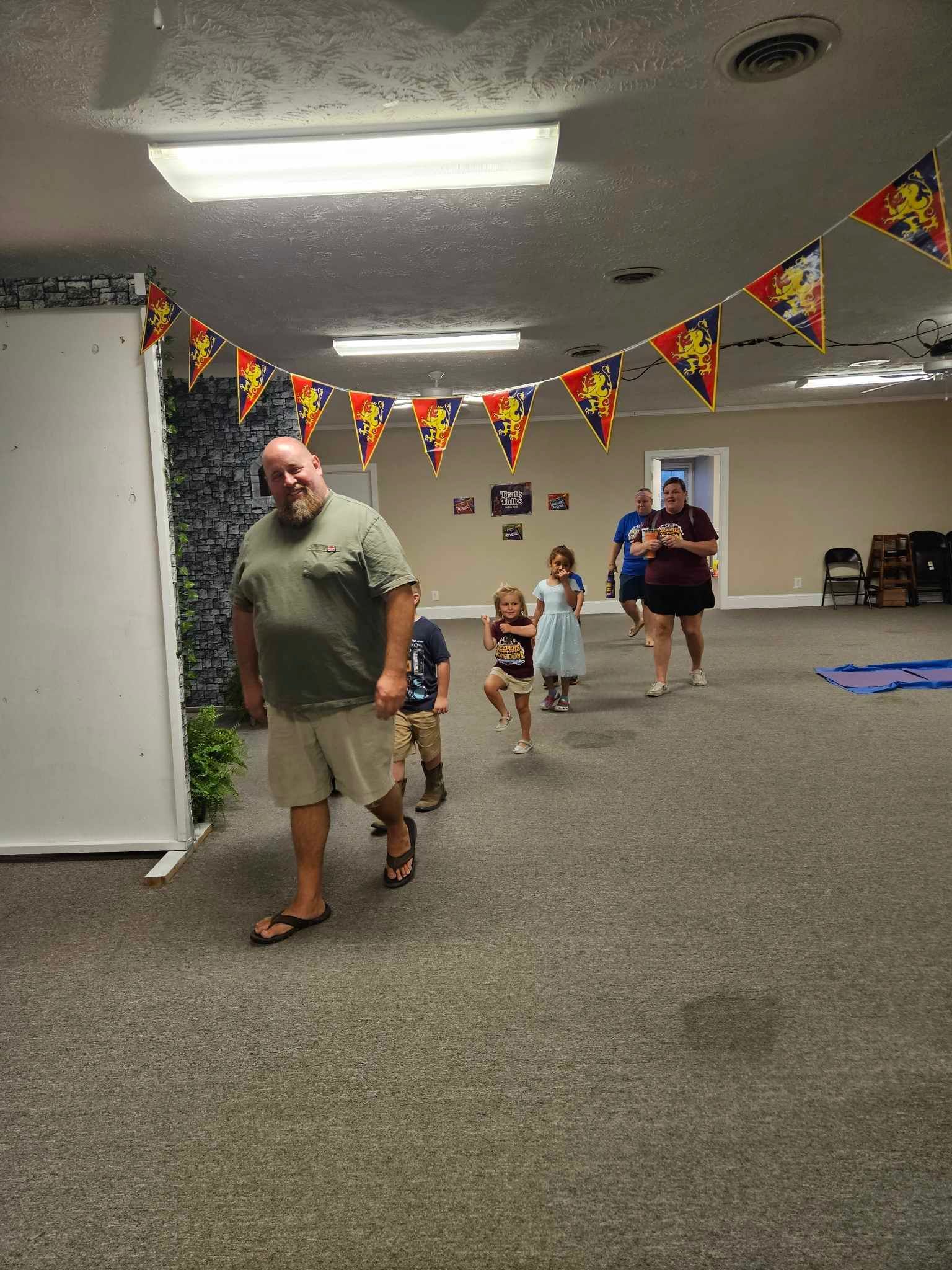 A group of people are walking through a room with flags hanging from the ceiling.