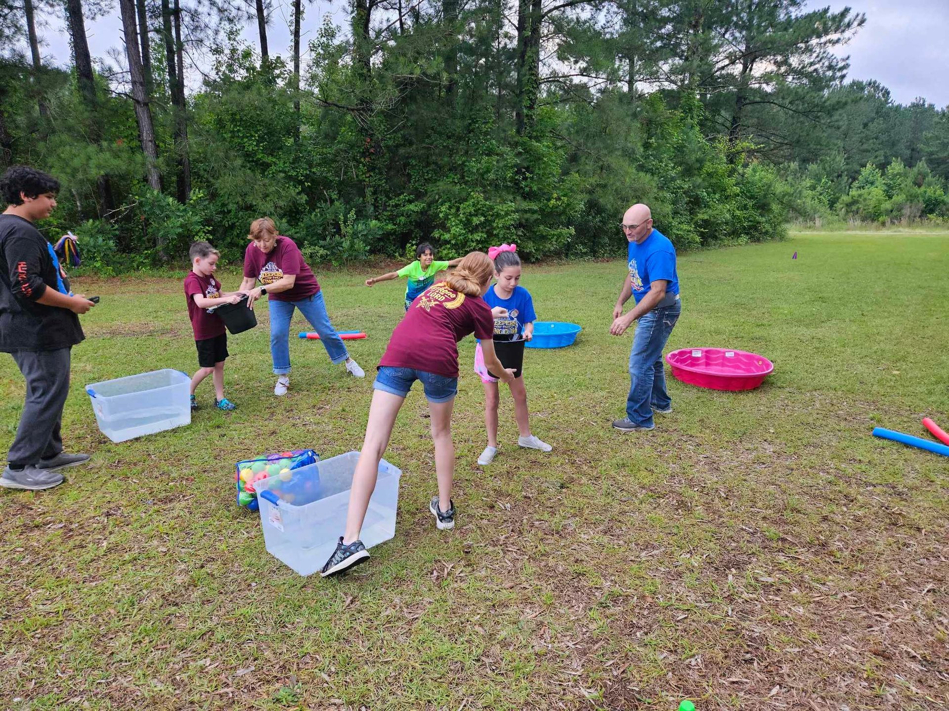 A group of people are playing a game of water balloons in a field.