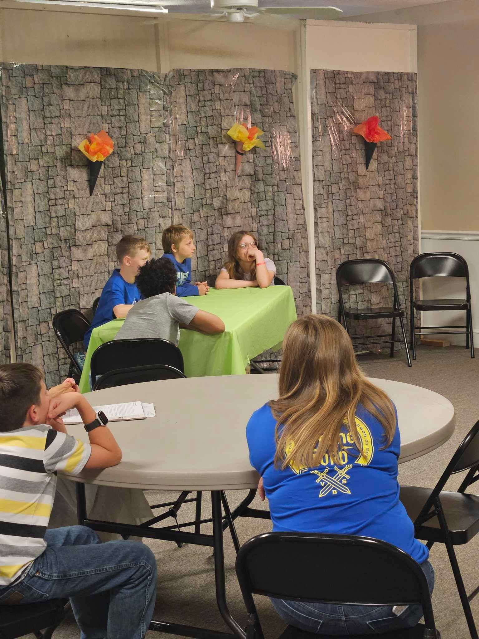 A group of children are sitting at tables in a room.