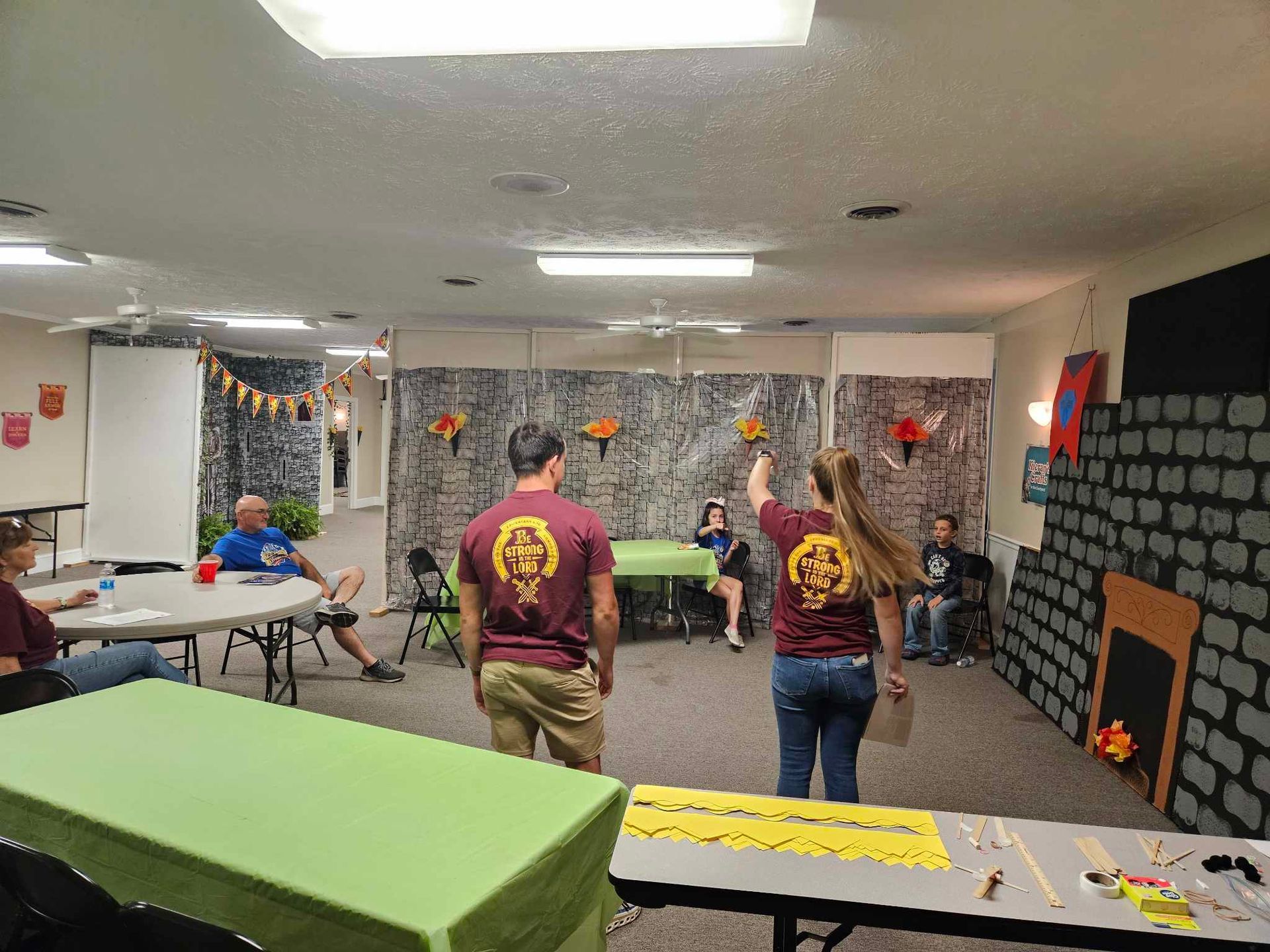 A group of people are standing around tables in a room.