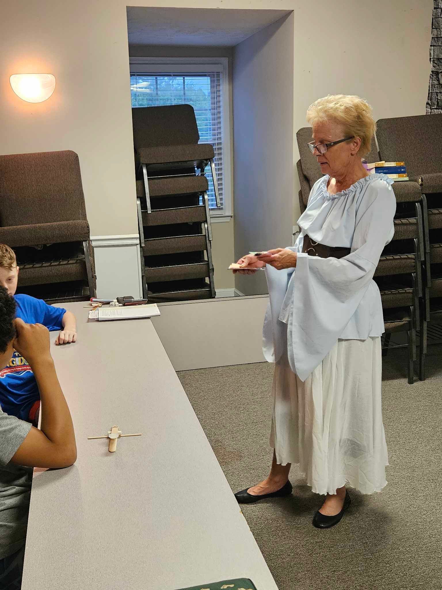 A woman standing in front of a table holding a plate of food