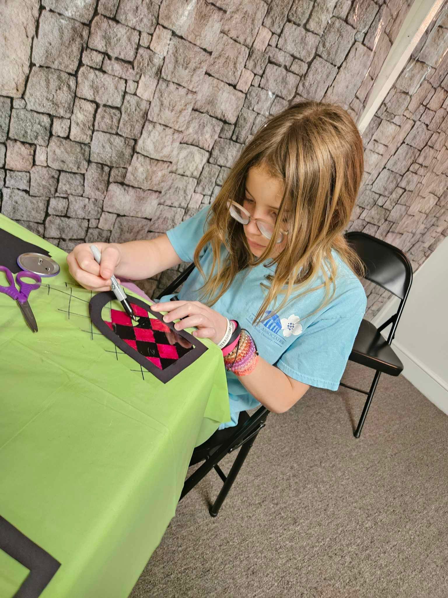 A young girl is sitting at a table cutting a piece of paper.