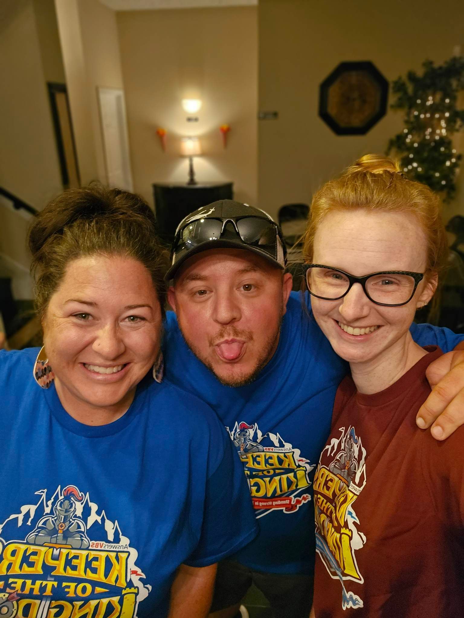 Three people posing for a picture with one wearing a shirt that says keeper