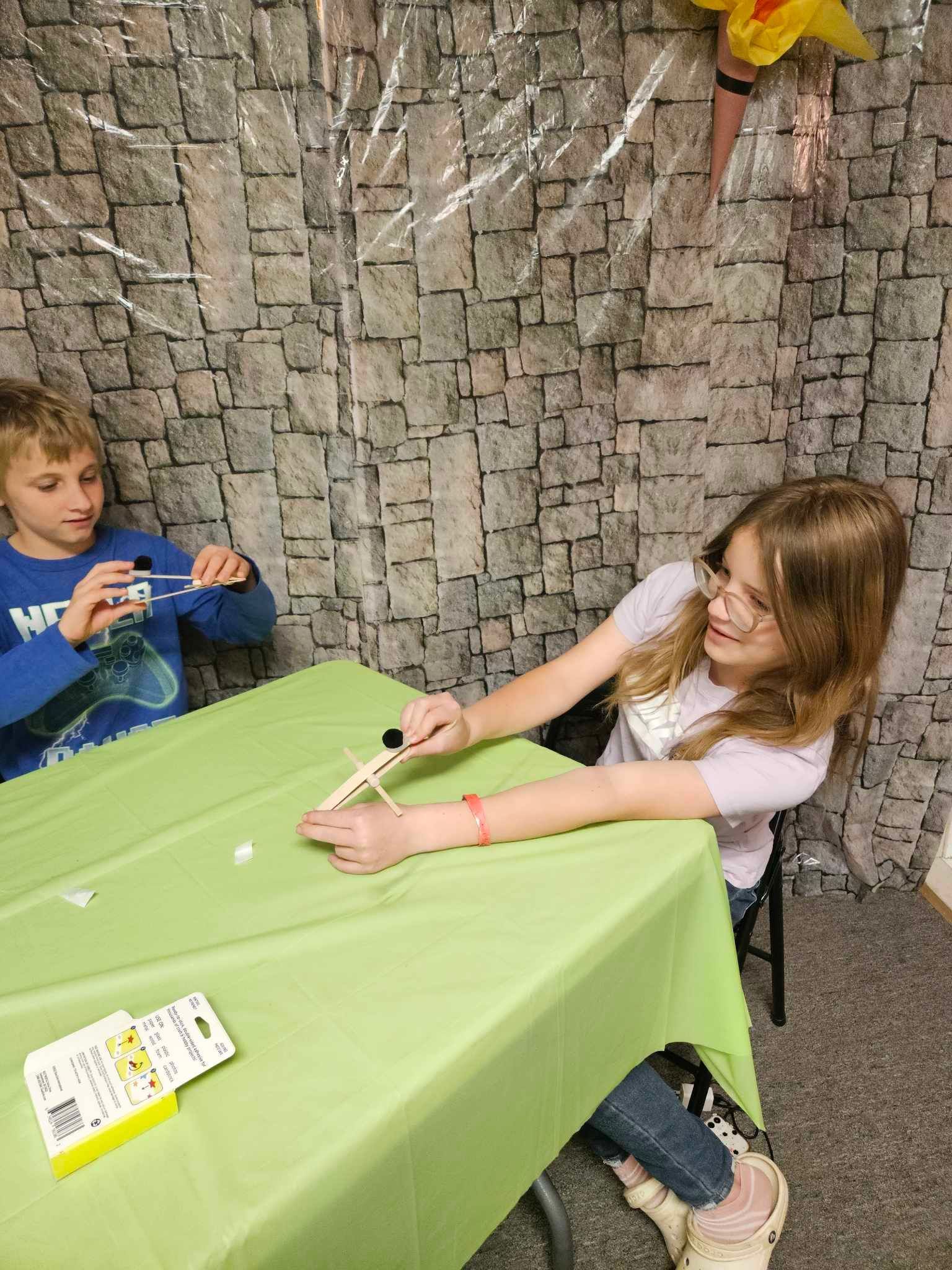 A boy and a girl are sitting at a table playing a game.