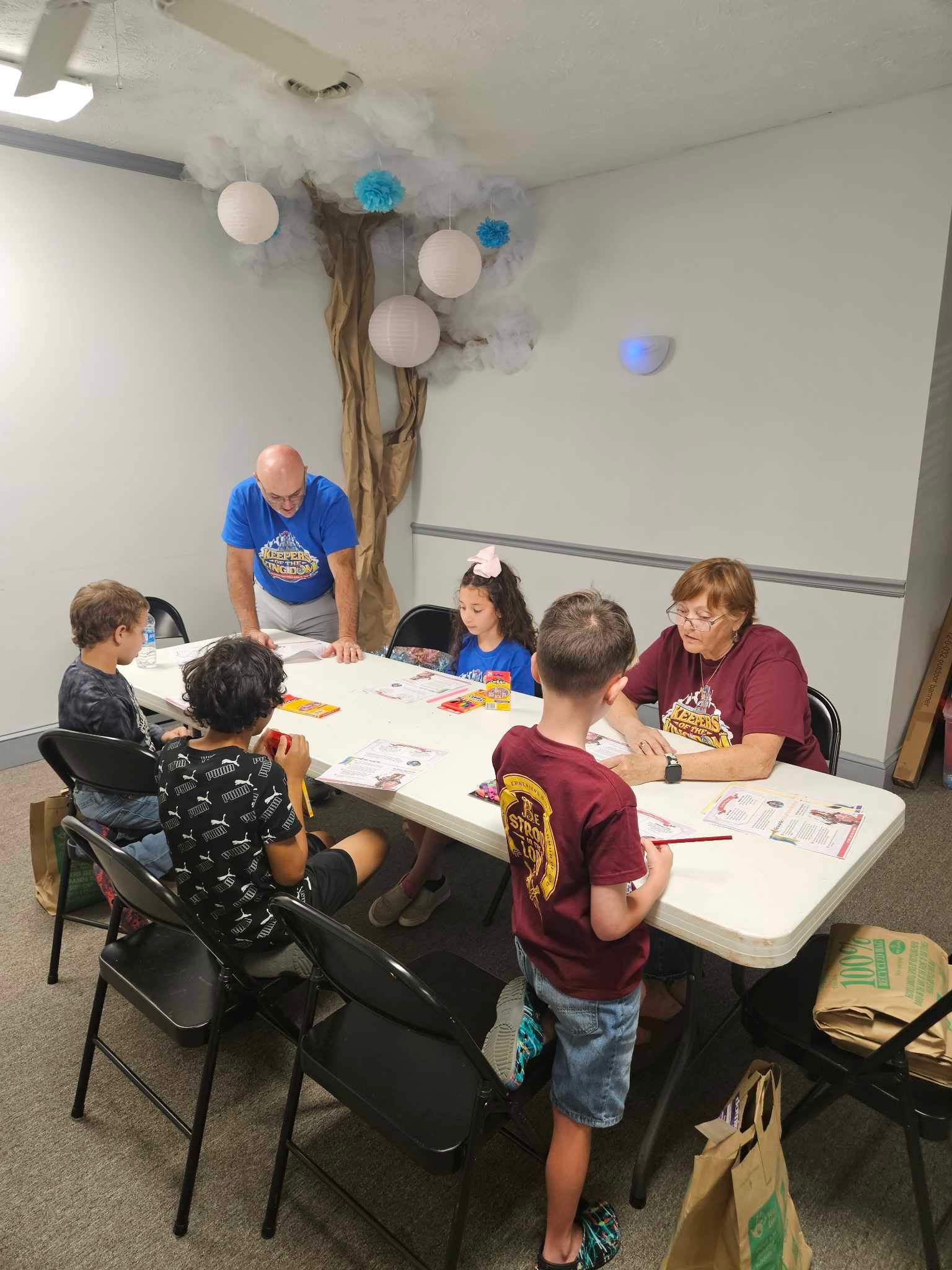 A group of children are sitting around a table in a room.