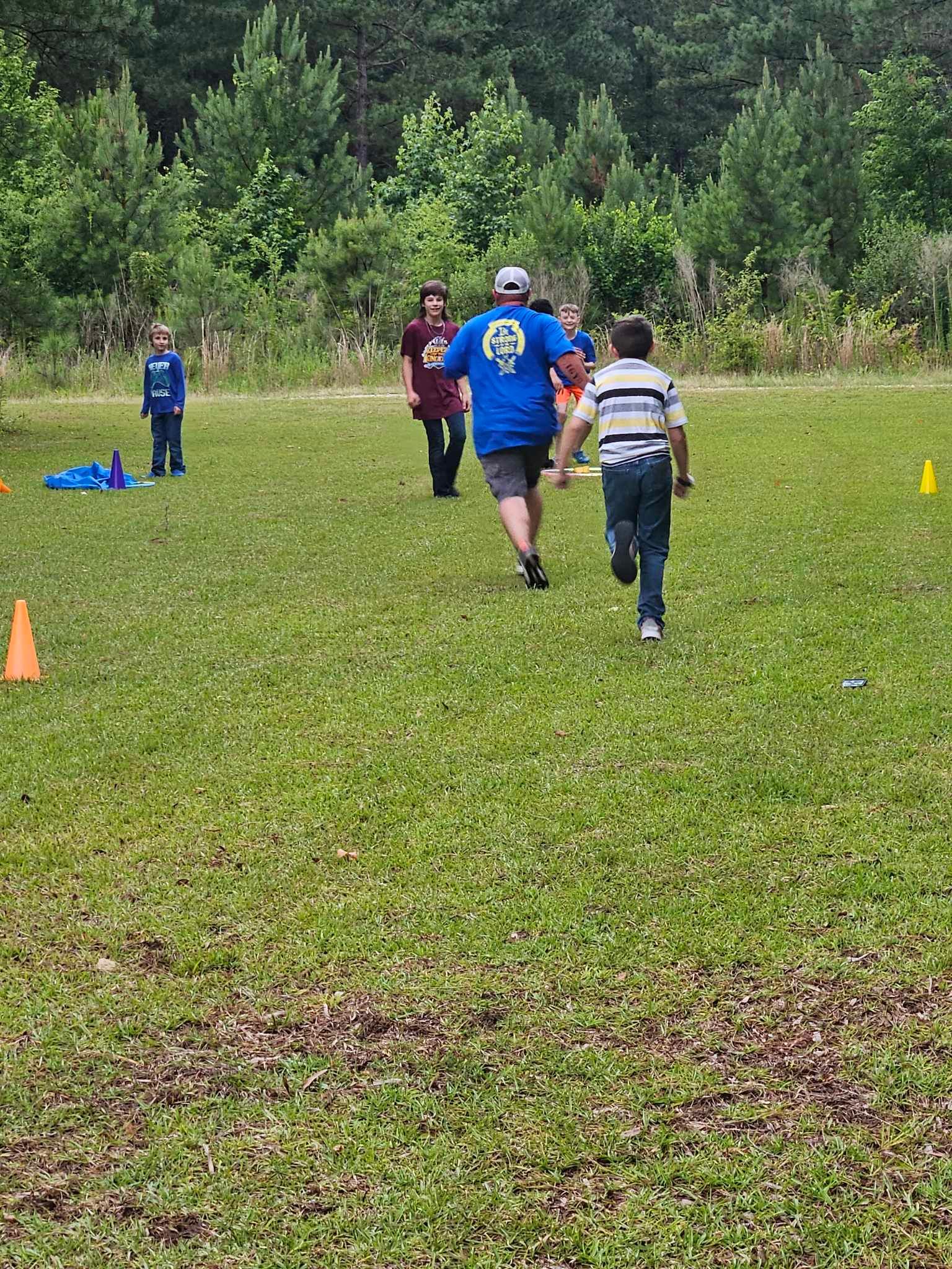 A group of children are running in a grassy field.