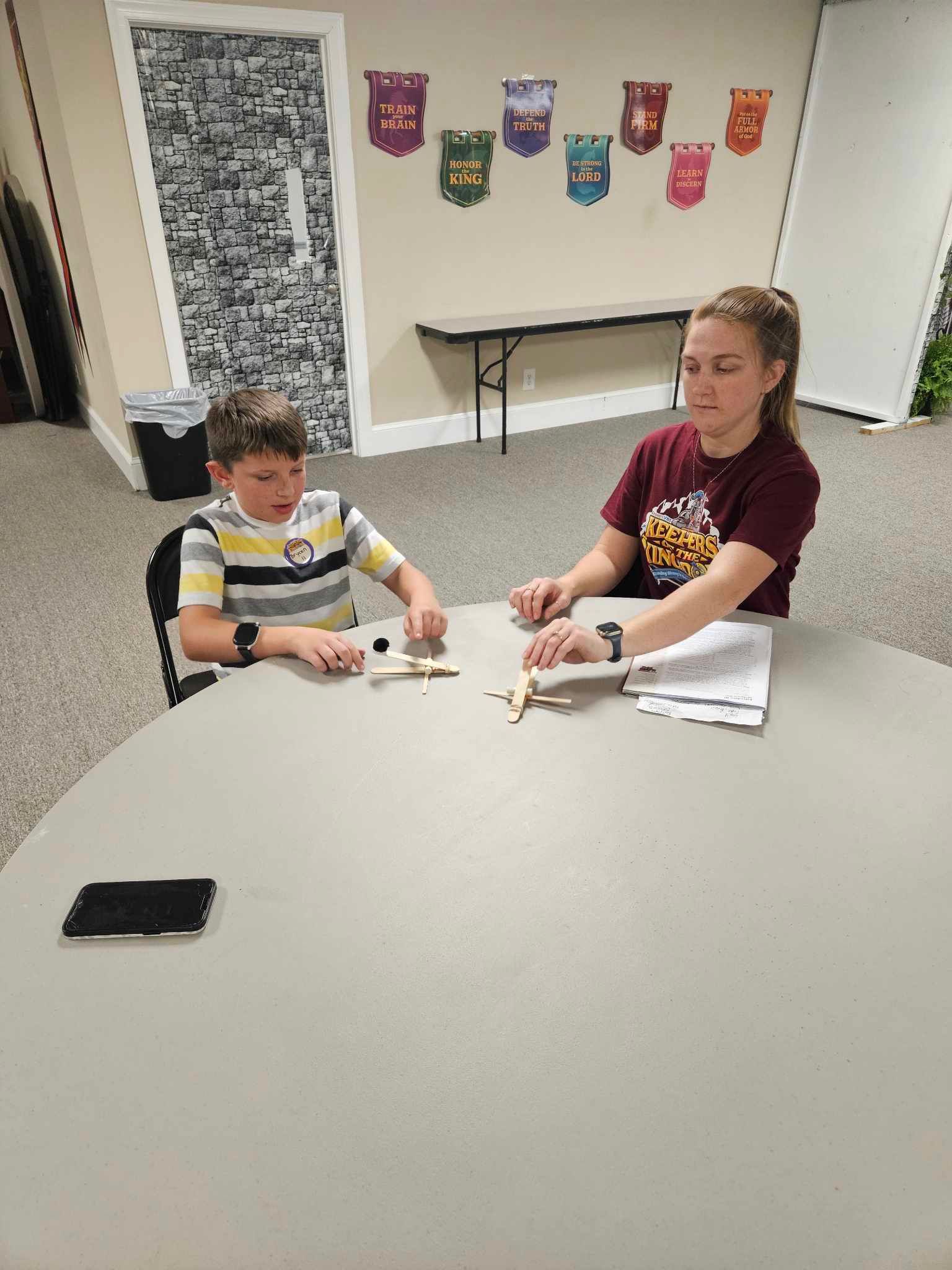 A boy and a girl are sitting at a table playing a game.