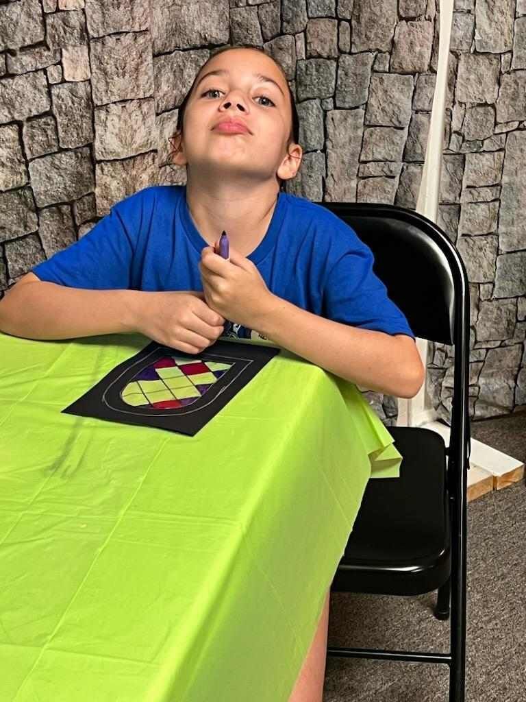 A young boy is sitting at a table with a green table cloth.