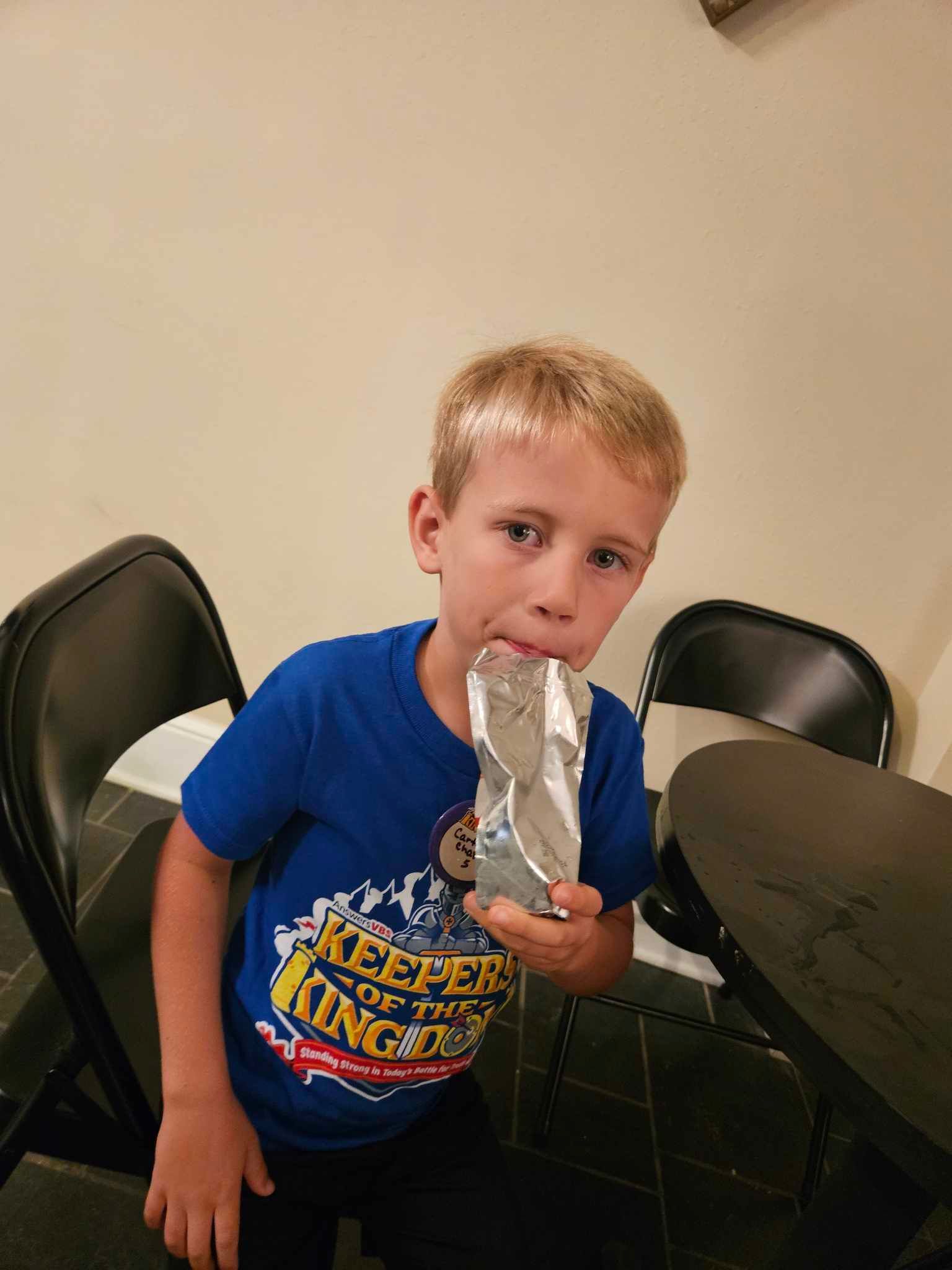 A young boy in a blue shirt is holding a trophy in his hand.