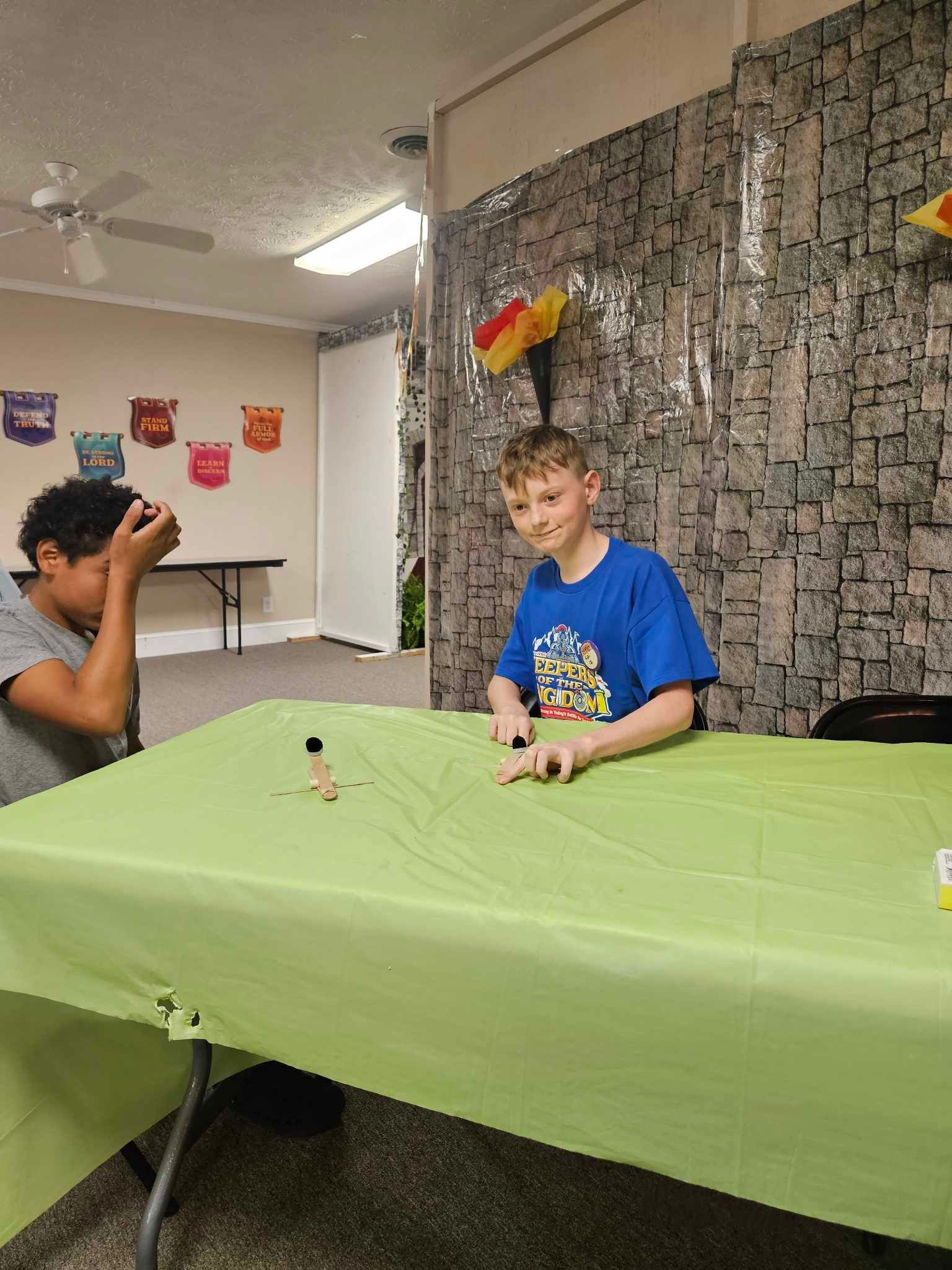 Two young boys are sitting at a table with a green tablecloth.