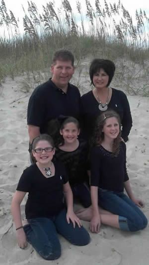 A family is posing for a picture on the beach.
