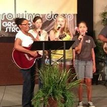 A group of people are standing on a stage singing into microphones.