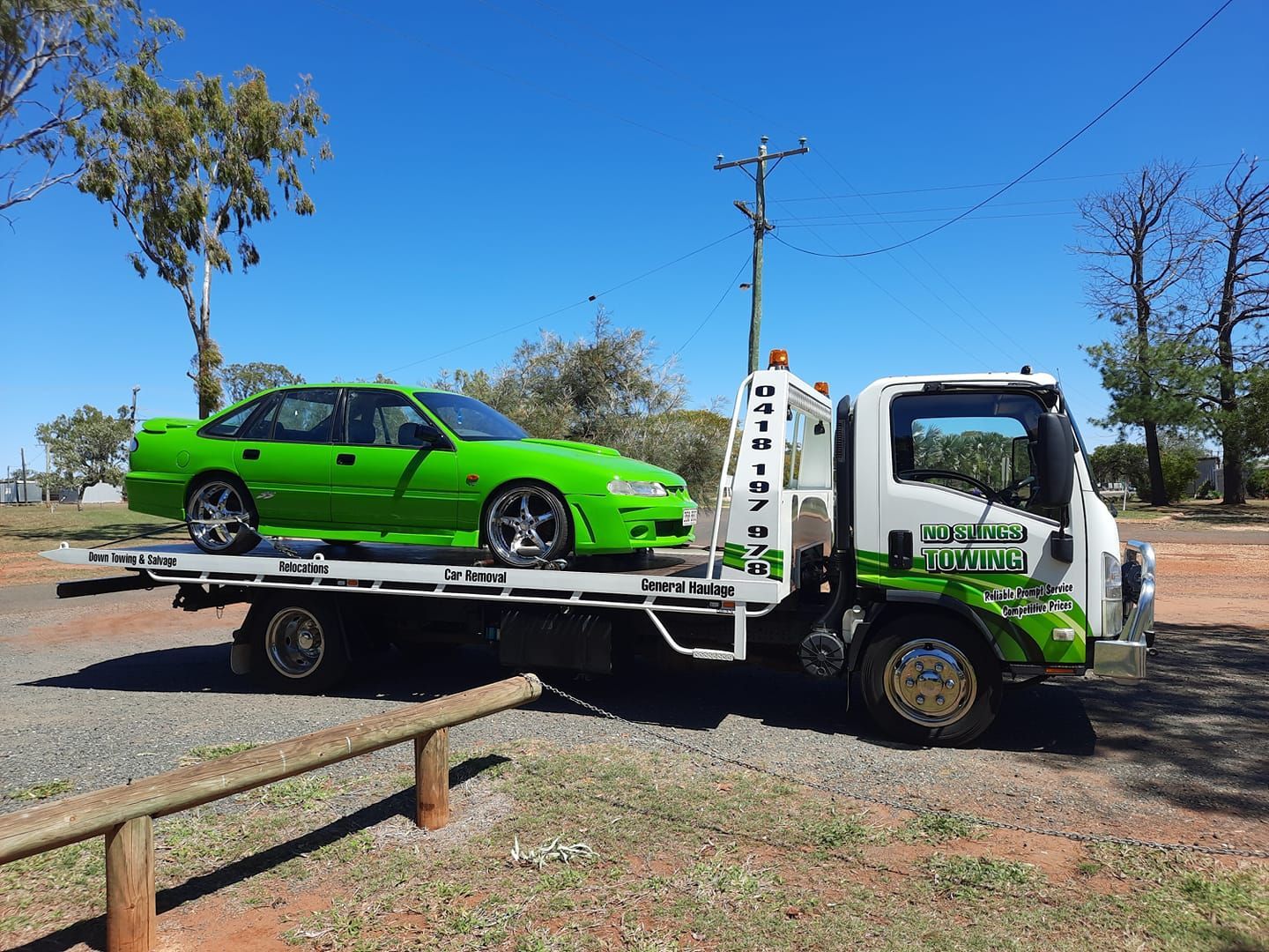 Green Car on a Flatbed Tow Truck Under a Blue Sky — No Slings Towing in Glendale, QLD