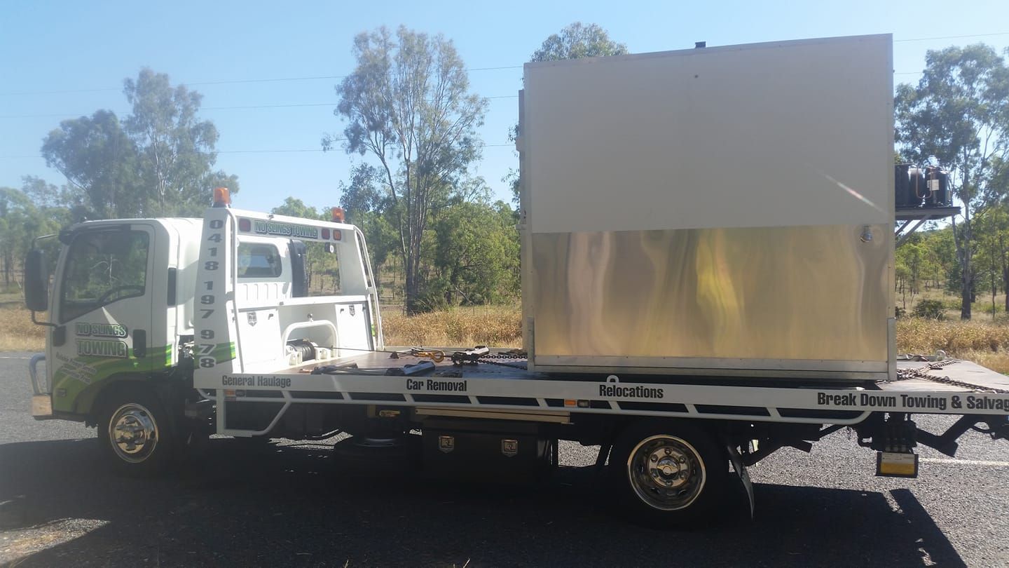 White Tow Truck Carrying a Large, Silver Metal Box Outdoors on a Sunny Day — No Slings Towing in Glendale, QLD