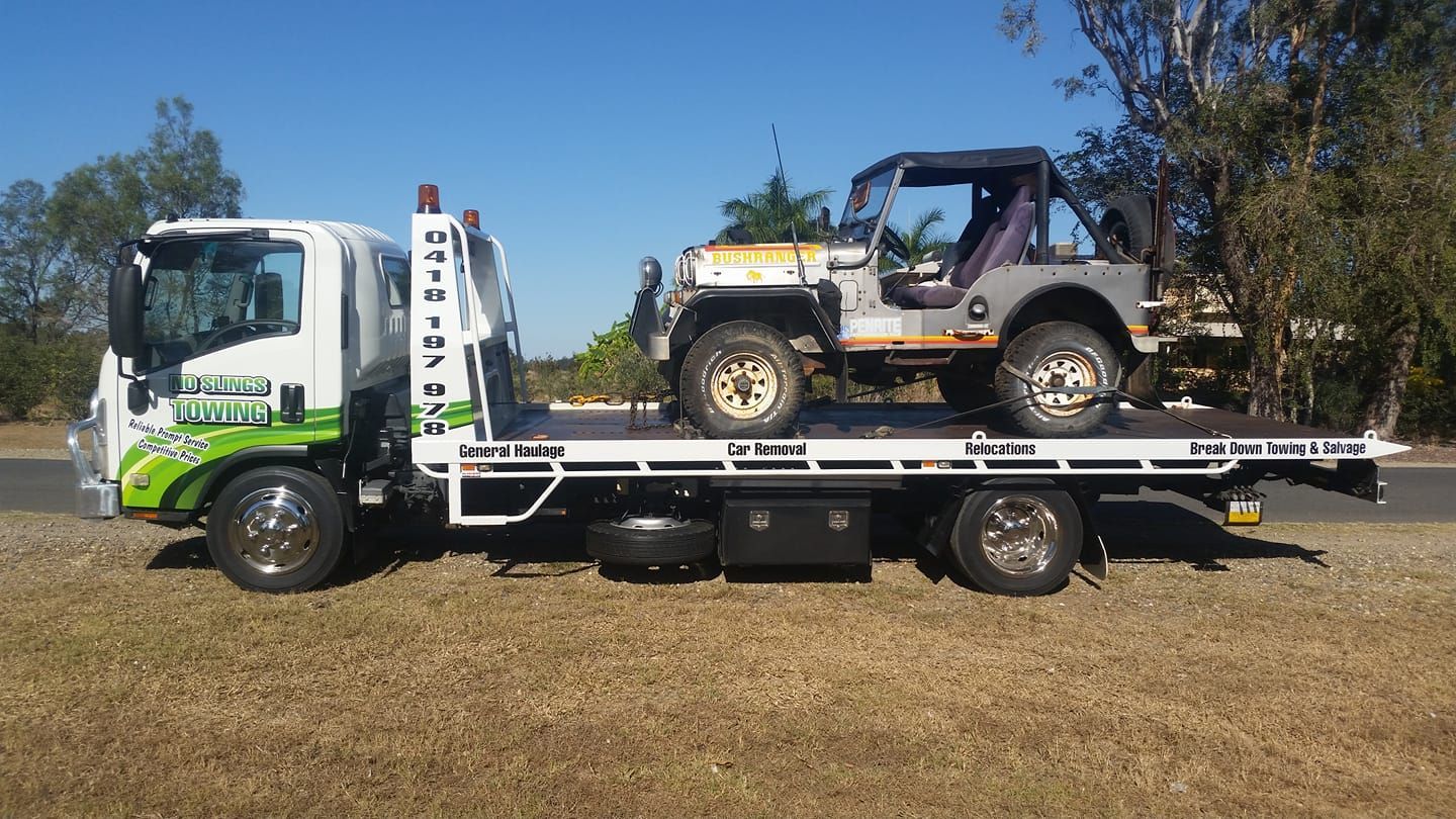 Tow Truck Hauling a Weathered, Beige Jeep on a Sunny Day — No Slings Towing in Glendale, QLD